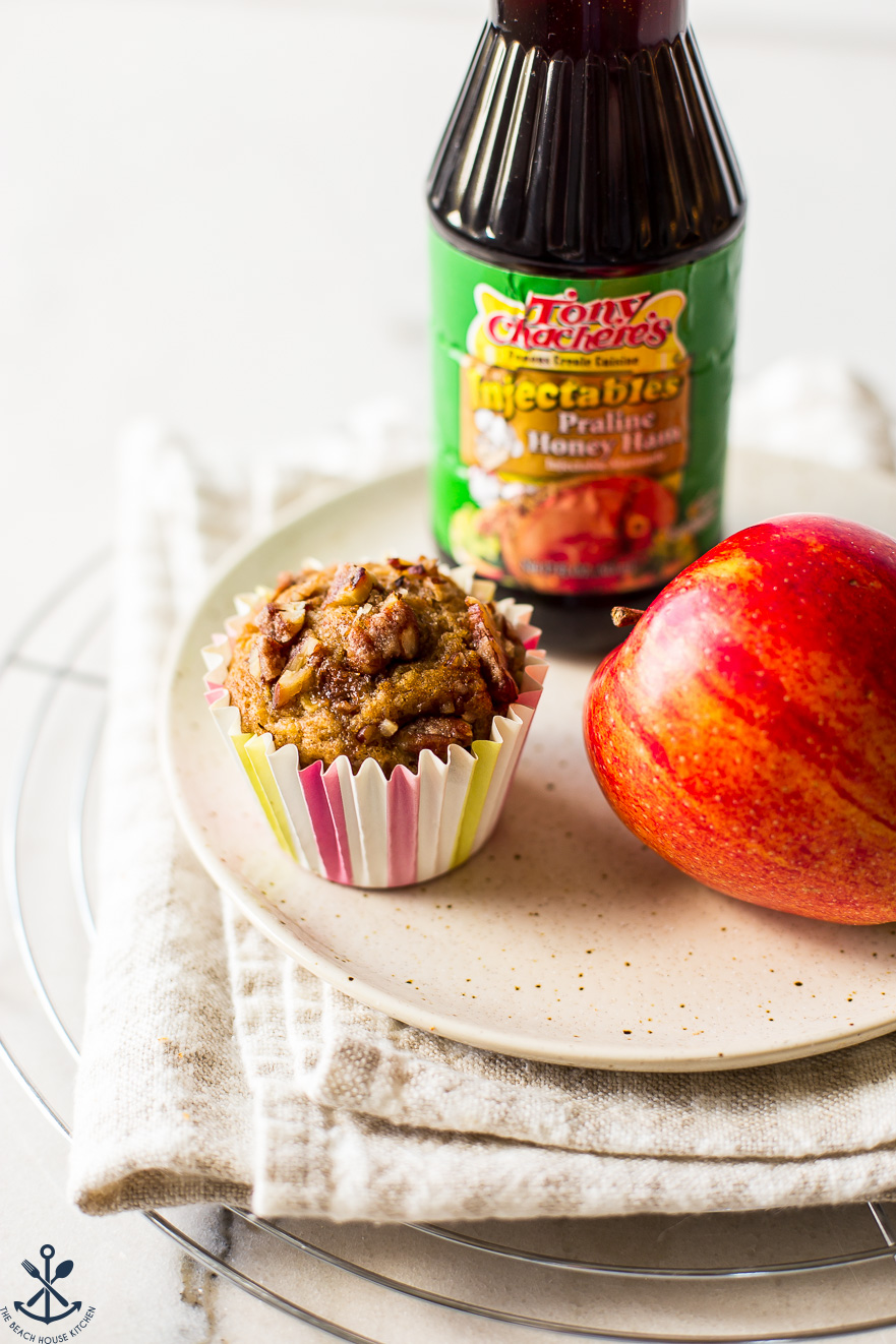 A muffin on a plate with an apple and a bottle of praline marinade