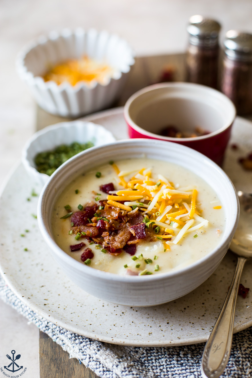Up close photo of a bowl of potato soup topped bacon and cheese
