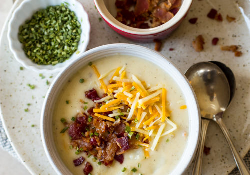 Up close overhead photo of a bowl of potato soup topped with bacon and shredded cheese