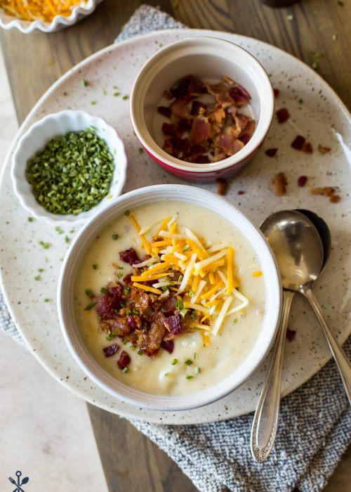 Up close overhead photo of a bowl of potato soup topped with bacon and shredded cheese