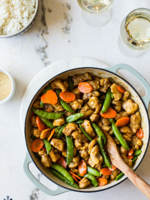 Overhead photo of a skillet of sesame chicken with carrots and sugar snap peas