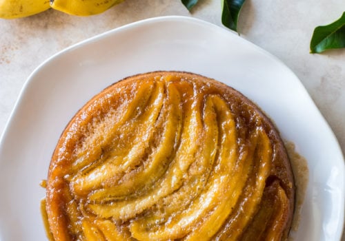 Overhead photo of a banana upside-down cake on a white platter