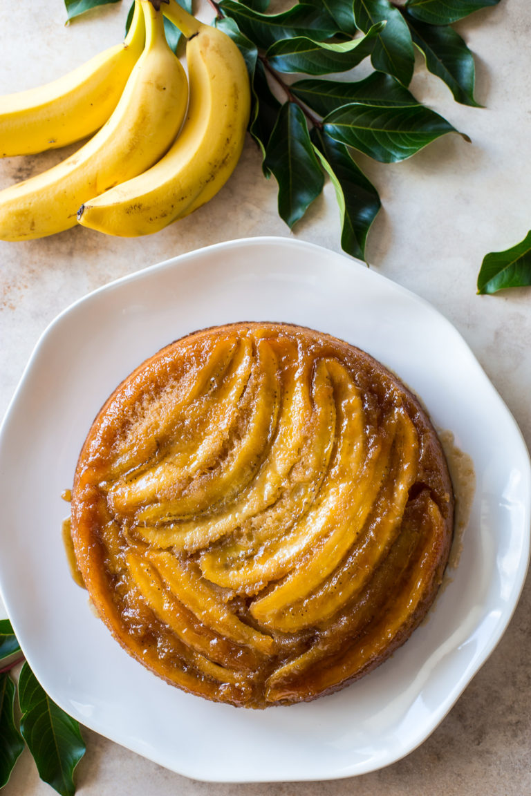 Overhead photo of a banana upside-down cake on a white platter