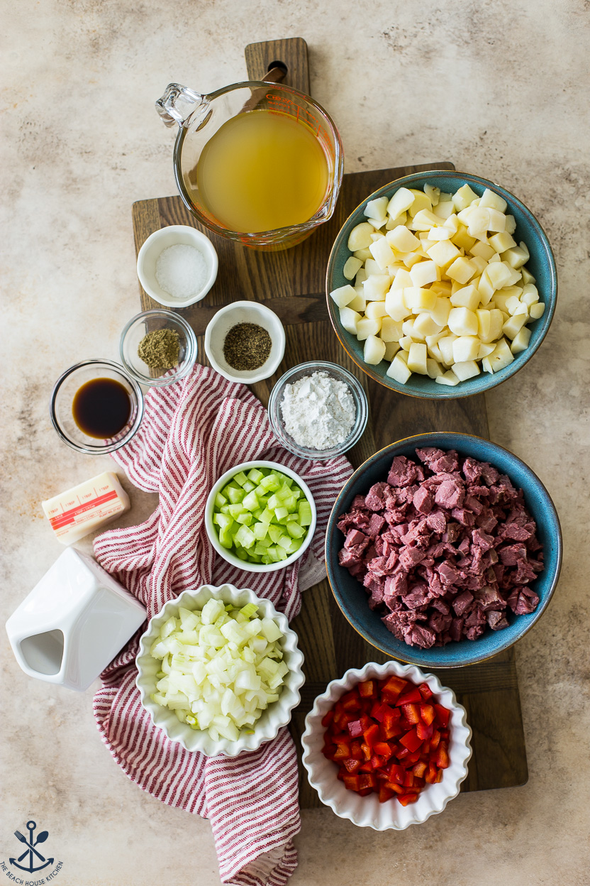 Overhead photo of ingredients for corned beef hash in bowls on a wooden board