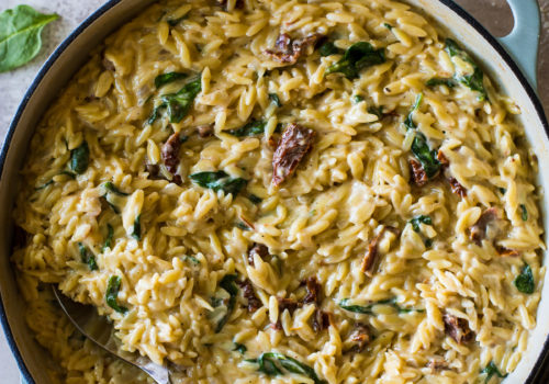 Overhead photo of a skillet filled with orzo, sun-dried tomatoes and spinach