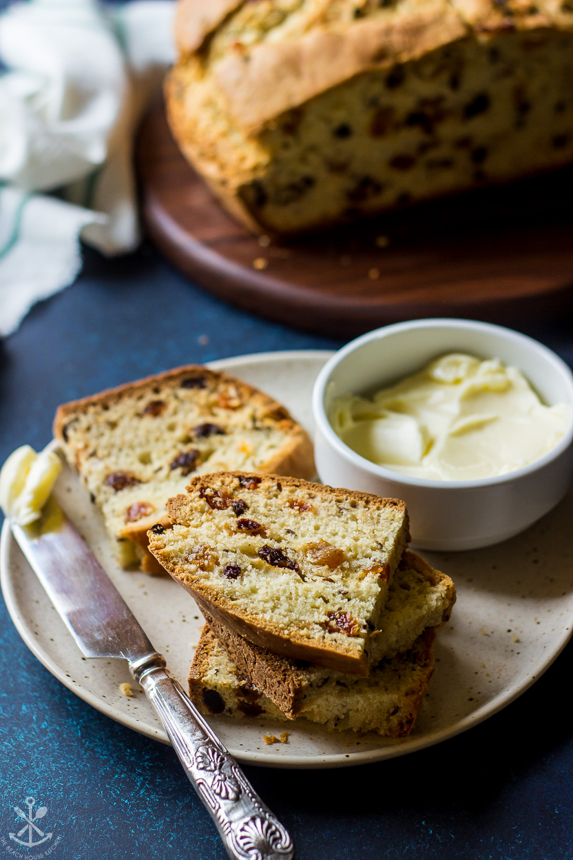A plate of slices of bread with raisins with a bowl of butter