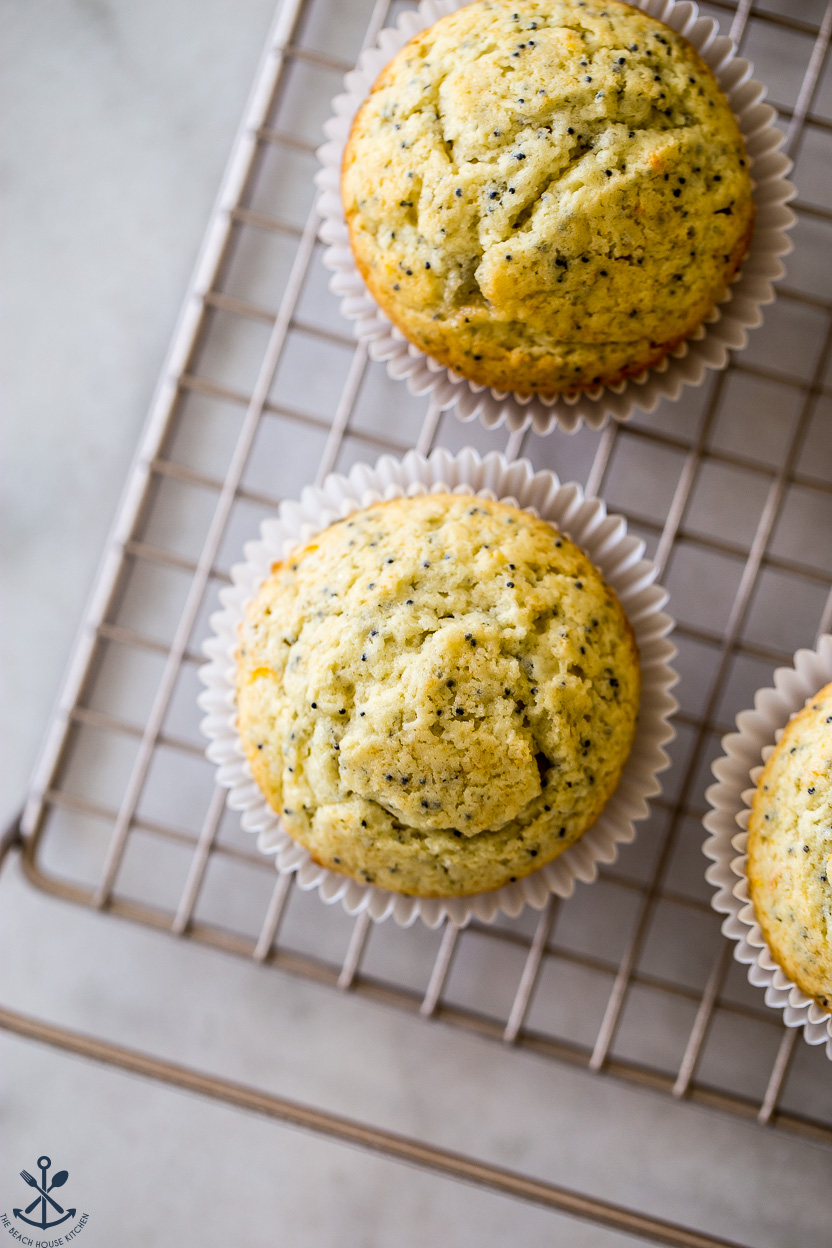 Up close overhead photo of lemon poppy seed muffins on a gold wire rack