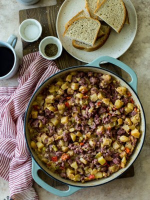 Overhead photo of a skillet of corned beef hash with a plate of rye bread slices