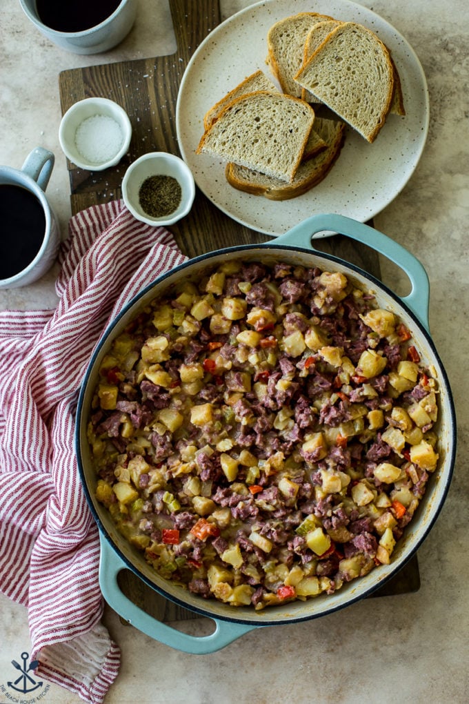 Overhead photo of a skillet of corned beef hash with a plate of rye bread slices