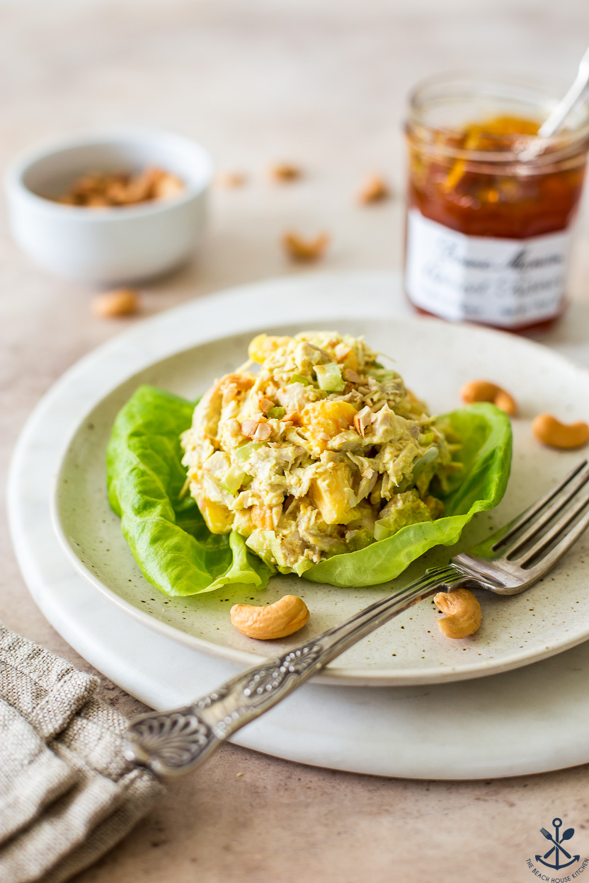 A scoop of curried chicken salad on a piece of lettuce on a plate