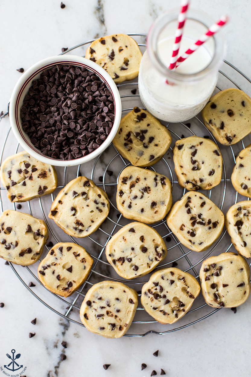 Overhead photo of chocolate chip shortbread cookies with a bowl of mini chocolate chips and a bottle of milk