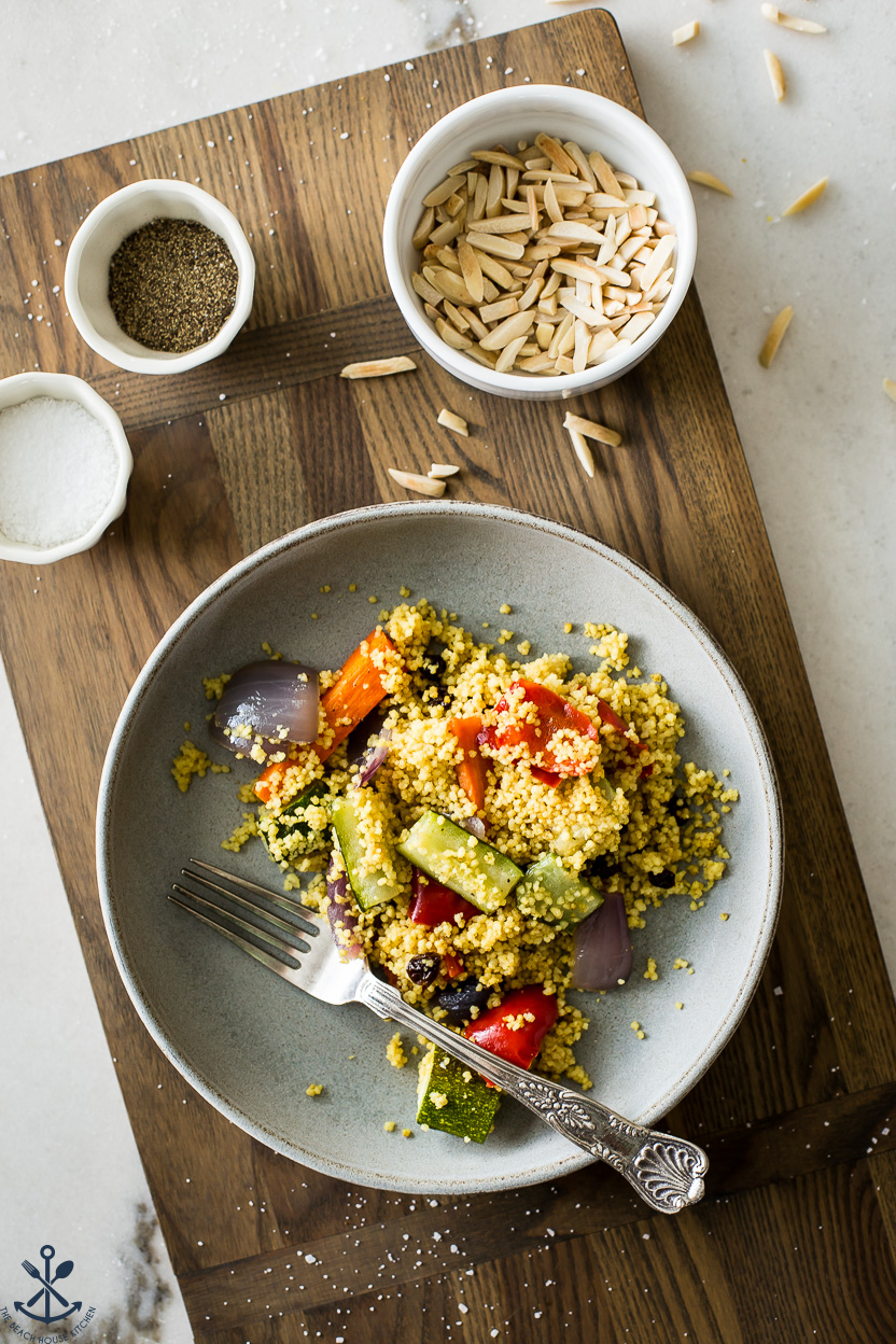Overhead photo of a plate of couscous with vegetables and a small bowl of slivered almonds