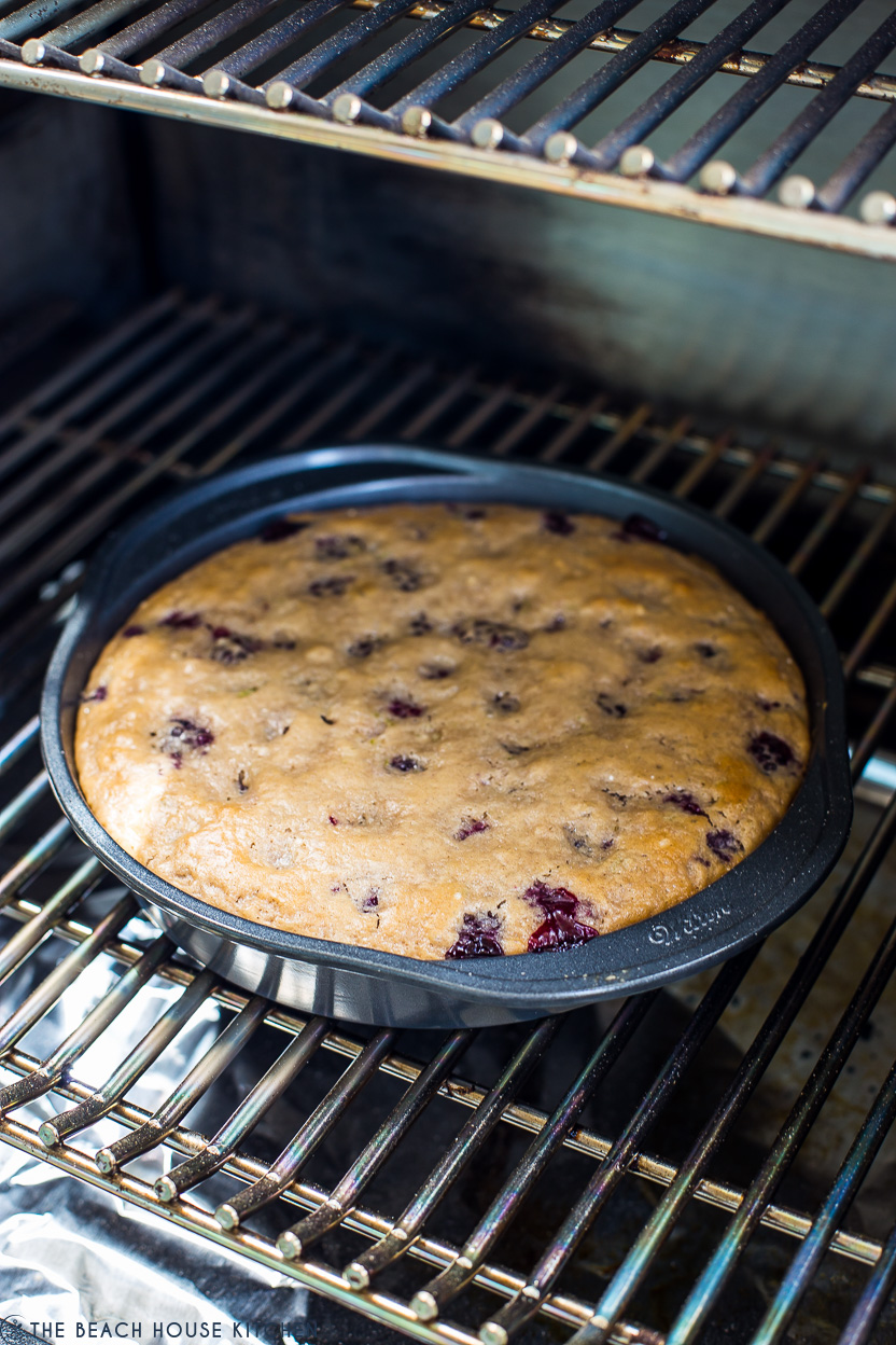A baked blackberry slump in a round baking pan on the grill