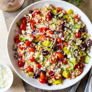 Overhead photo of a Greek Couscous Salad in a round white bowl