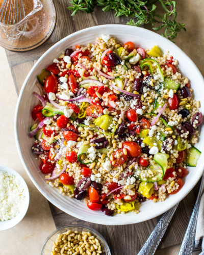 Overhead photo of a Greek Couscous Salad in a round white bowl