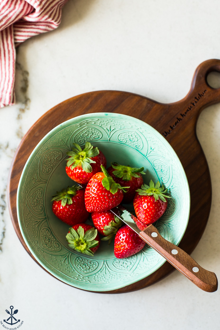 Overhead photo of a green bowl filled with strawberries