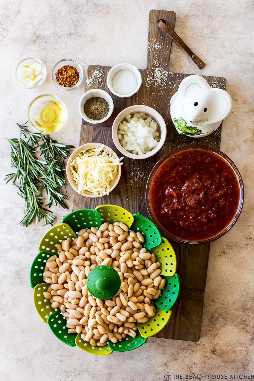 Overhead photo of ingredients for Italian Baked Beans in bowls on a wooden board