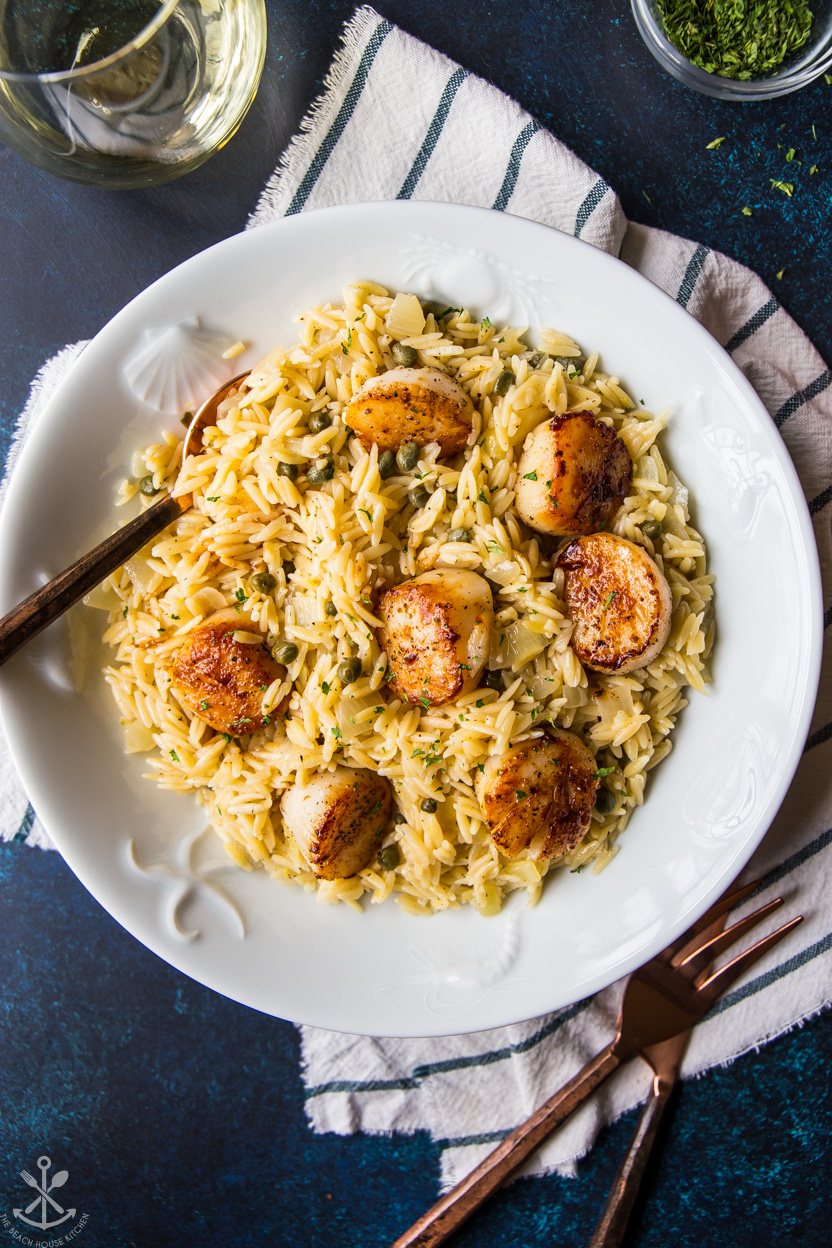 Overhead photo of a white dish of scallops with orzo pasta