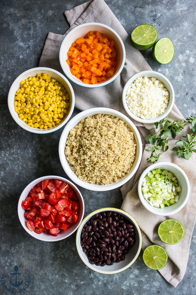Overhead photo of ingredients for a quinoa salad in bowls on a gray background