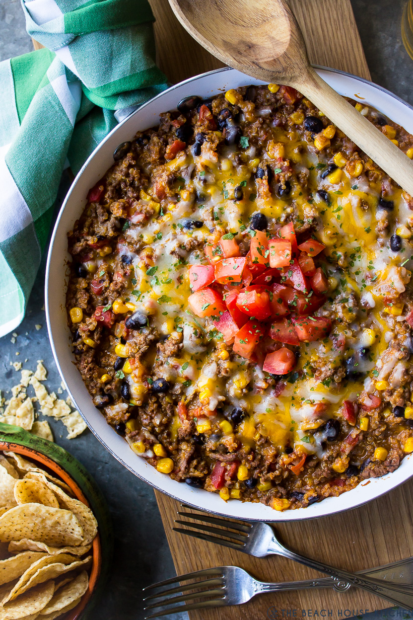 Up close overhead photo of a skillet filled with beef and quinoa topped with chopped tomatoes