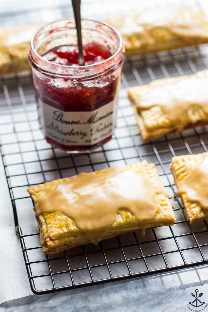 Peanut butter glazed pop tarts on a wire rack with a jar of preserves