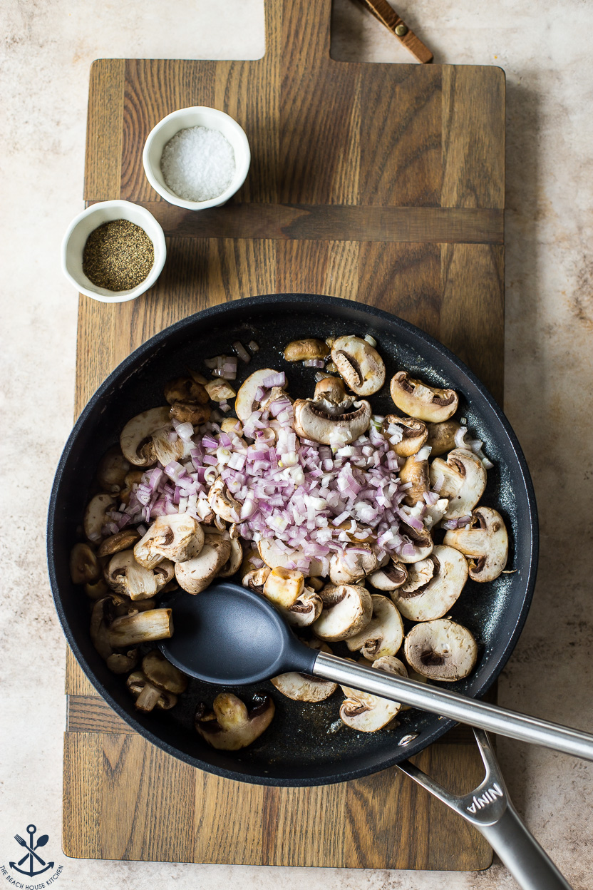 Overhead photo of a skillet filled with pre-cooked mushrooms and onions