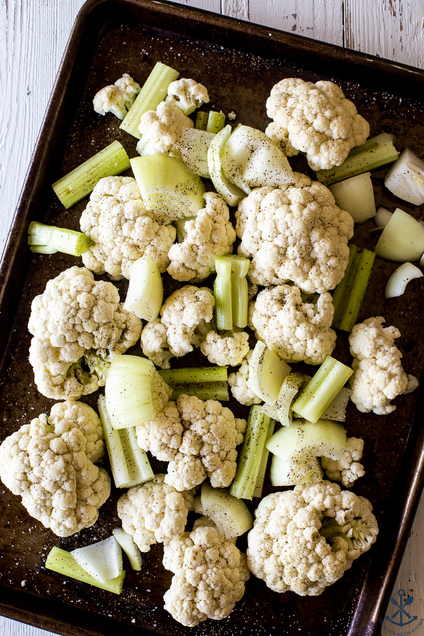 A baking sheet filled with pre-cooked cauliflower, celery and onions