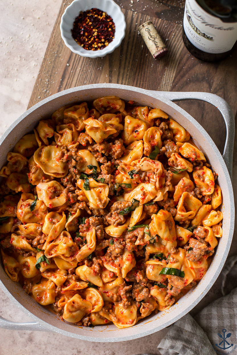 Up close overhead photo of a skillet of tortellini with Italian sausage