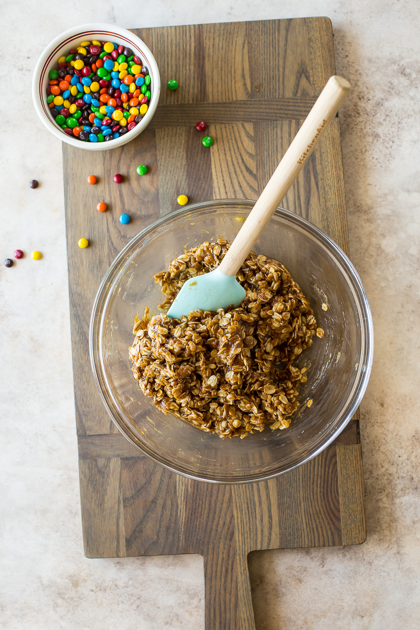 Overhead photo of a bowl of an oatmeal cookie mixture and a small bowl of M&M's