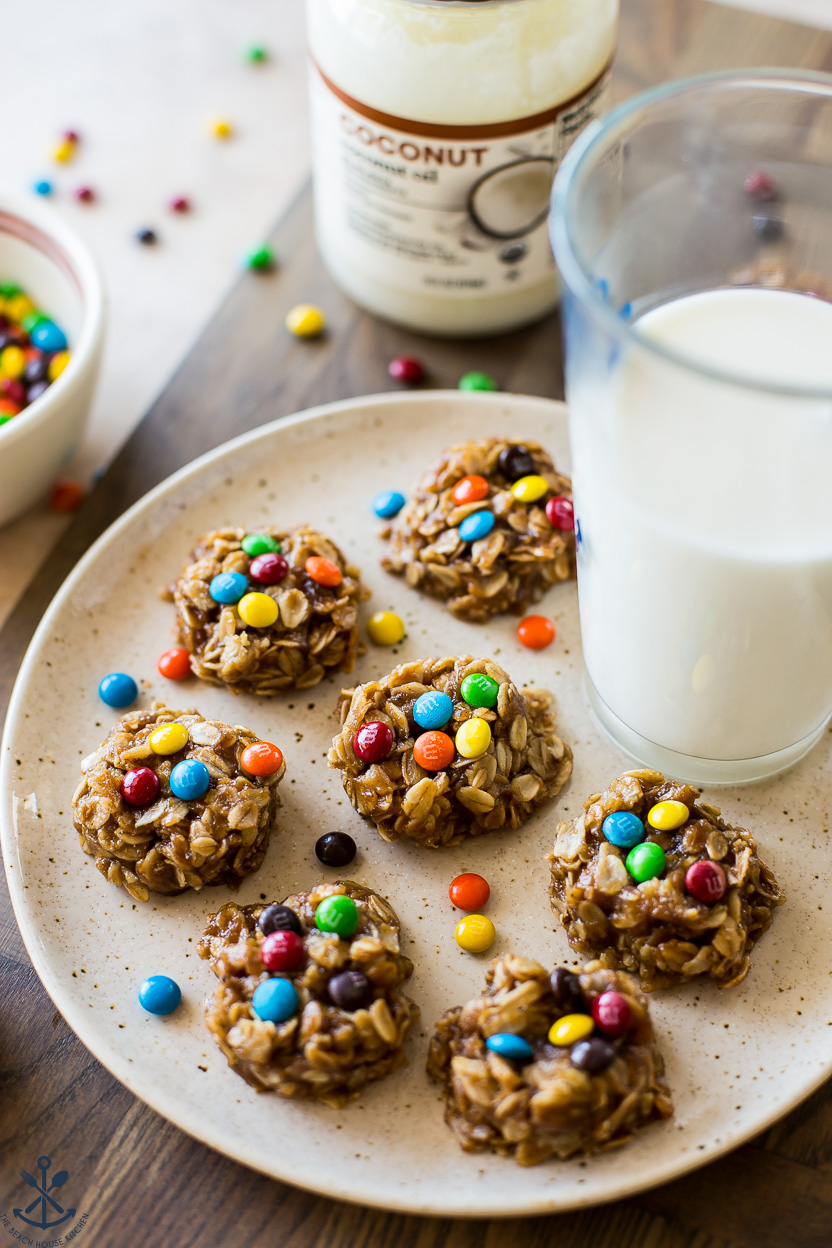 A plate of no bake cookies topped with mini M&M's with a glass of milk