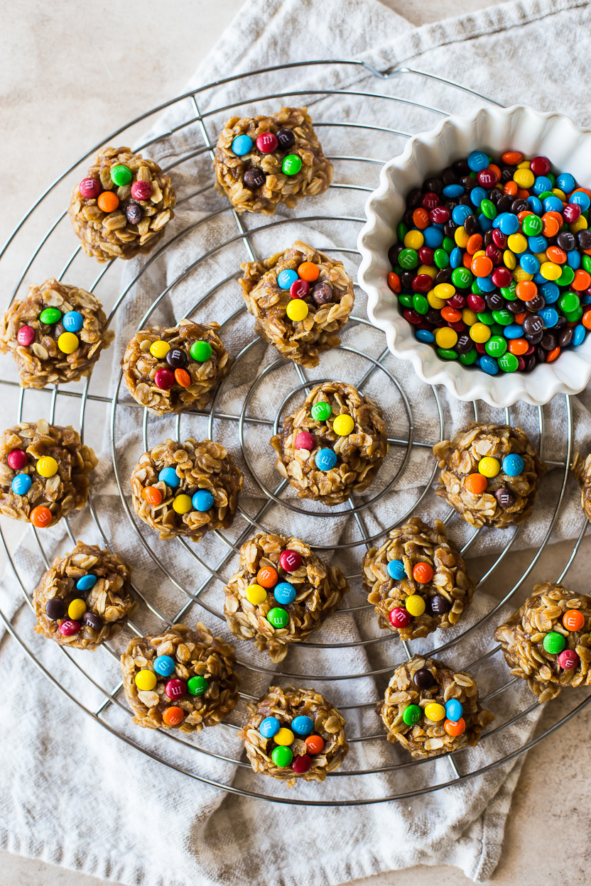 Overhead photo of no bake cookies topped with mini M&M's on a round wire rack with a small bowl of M&M's