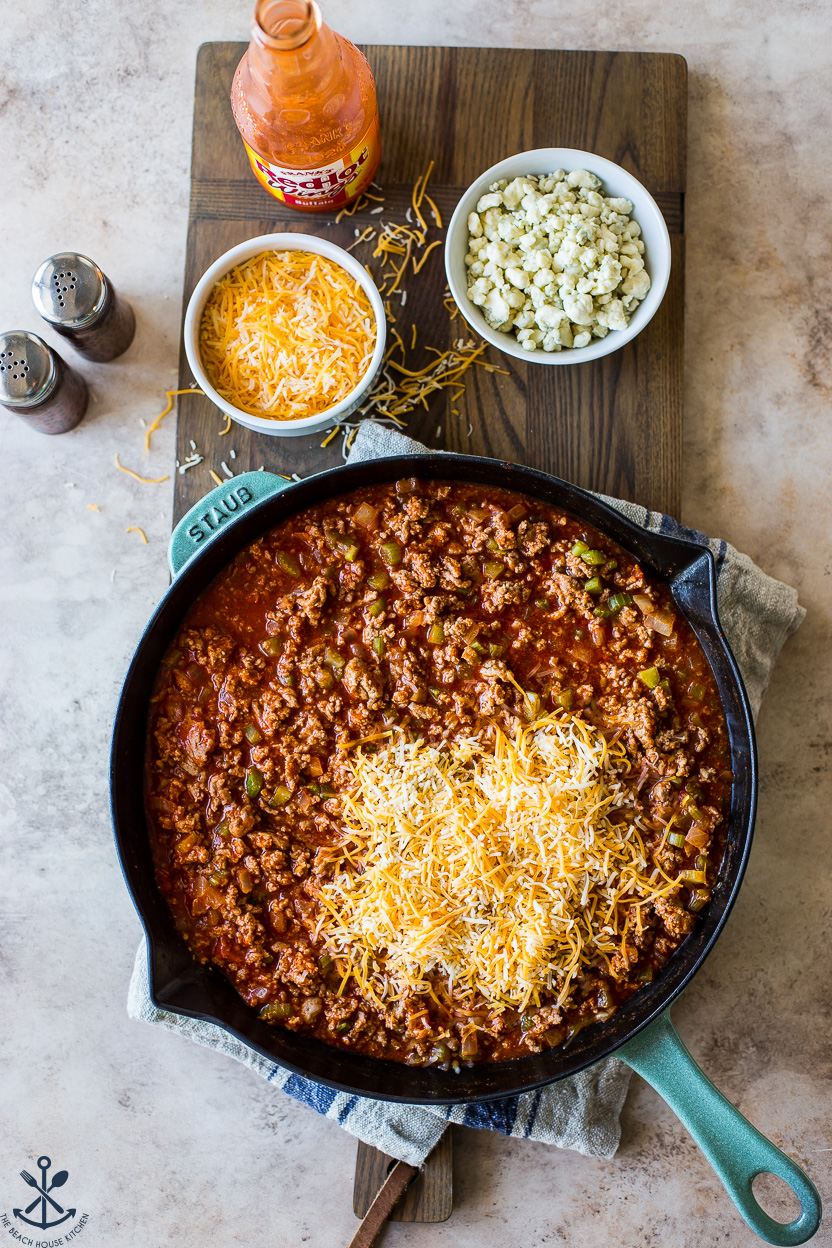 Overhead photo of a skillet of buffalo sloppy joes topped with shredded cheddar jack