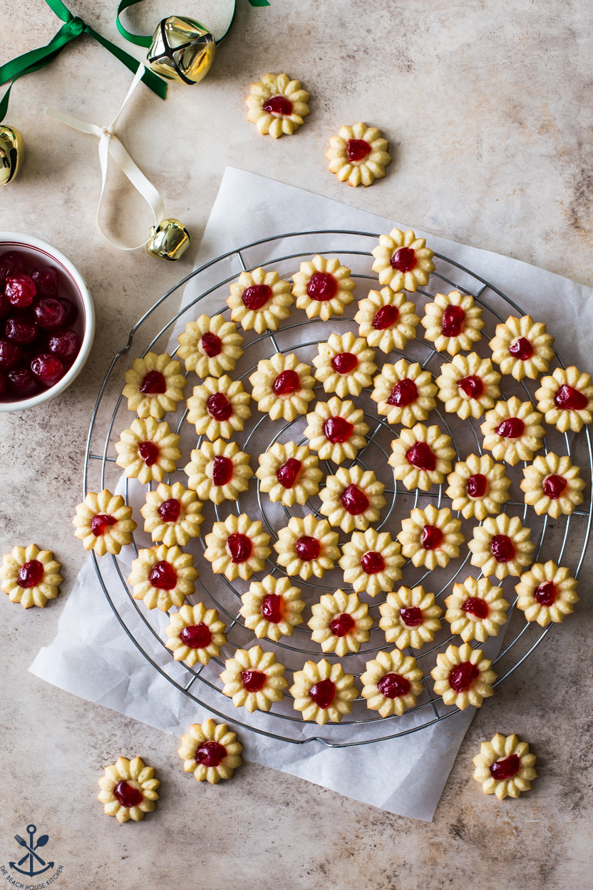 Overhead photo of spritz cookies topped with a cherry on a round wire rack