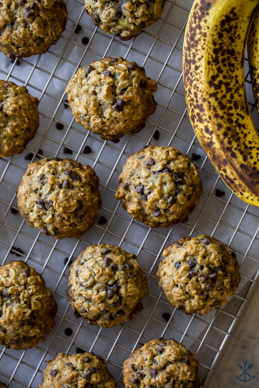 Overhead photo of oatmeal chocolate chip banana cookies on a wire rack with a banana off to the side