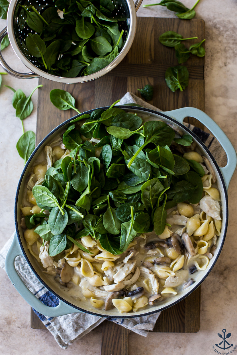 Overhead photo of a deep skillet filled with pasta and turkey topped with spinach leaves