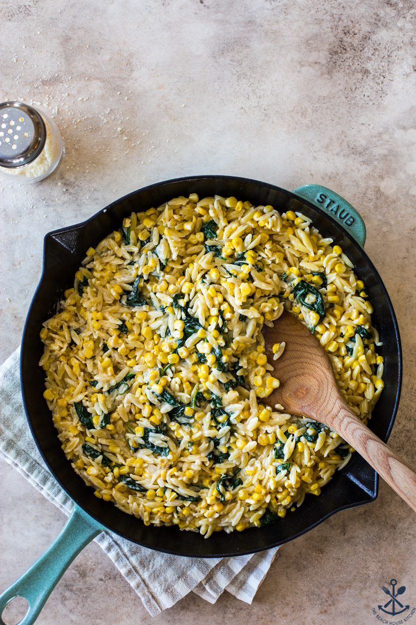Overhead photo of a skillet or creamy corn and spinach orzo