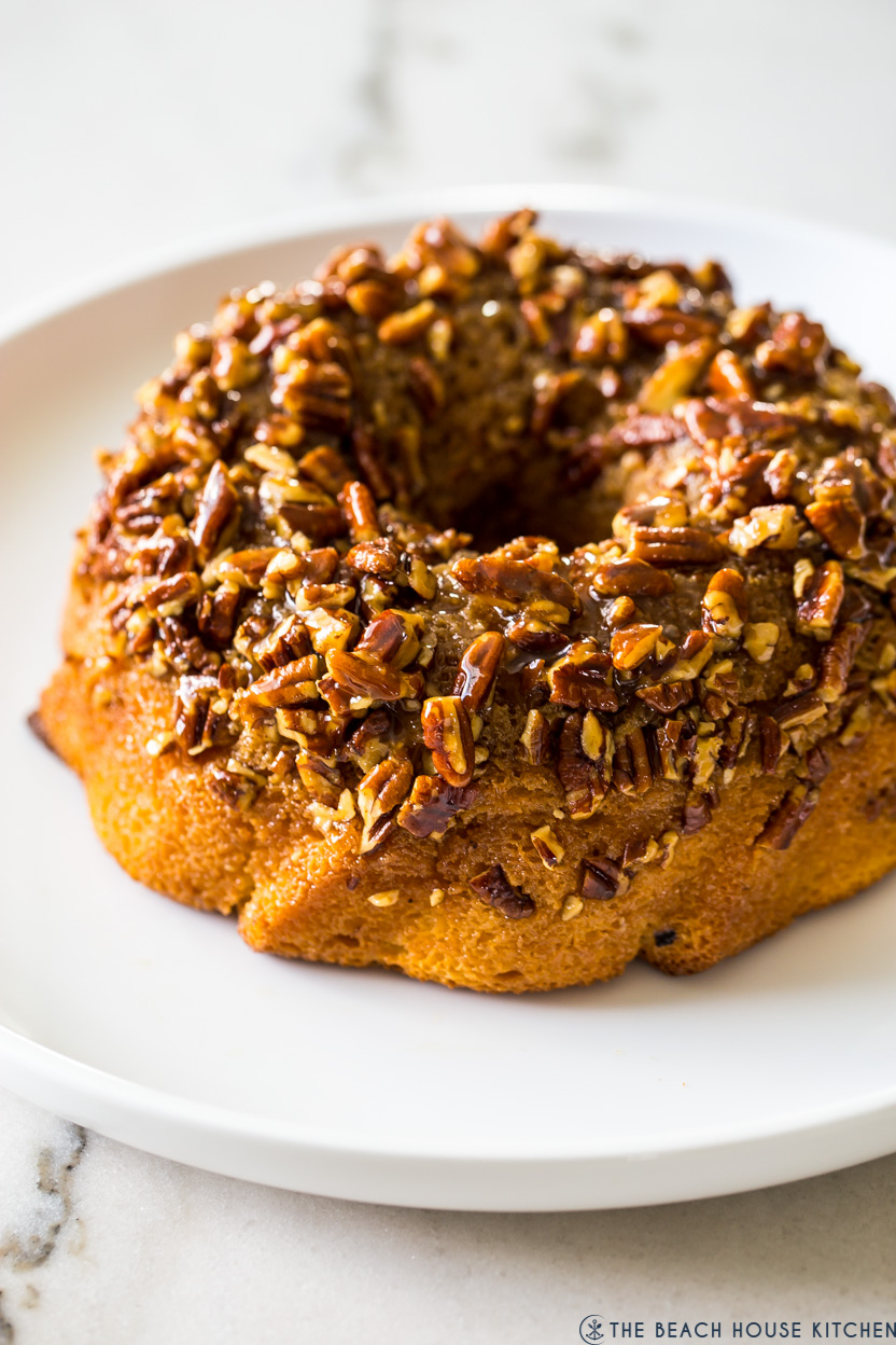 A bundt cake topped with pecans on a white platter