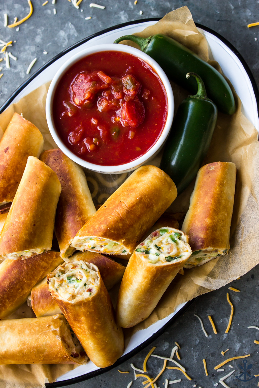 Up close overhead photo of Cheesy Bacon Jalapeño Taquitos with a bowl of salsa