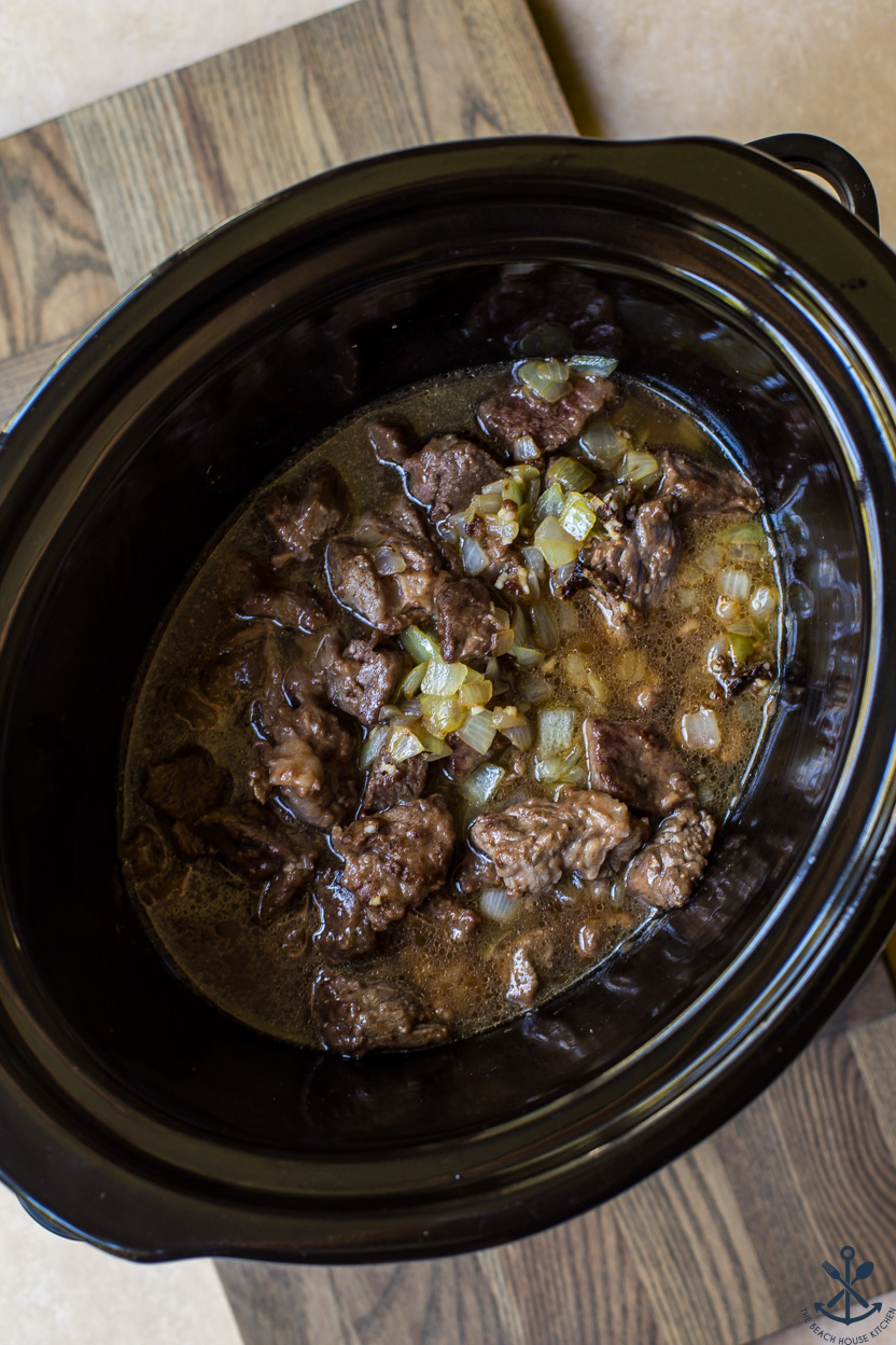 Overhead photo of a slow cooker of beef and onions