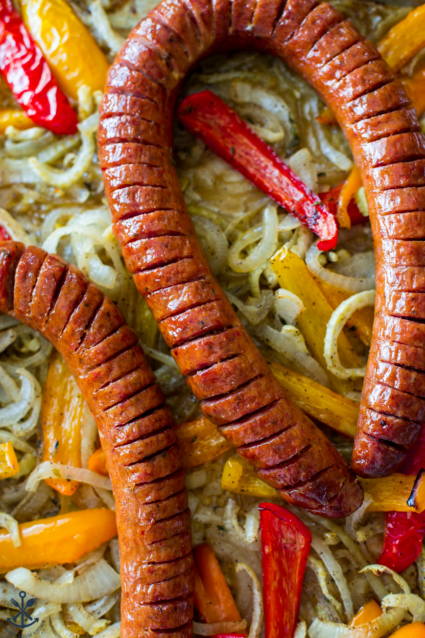 Up close overhead photo of a sheet pan of kielbasa, onions and peppers
