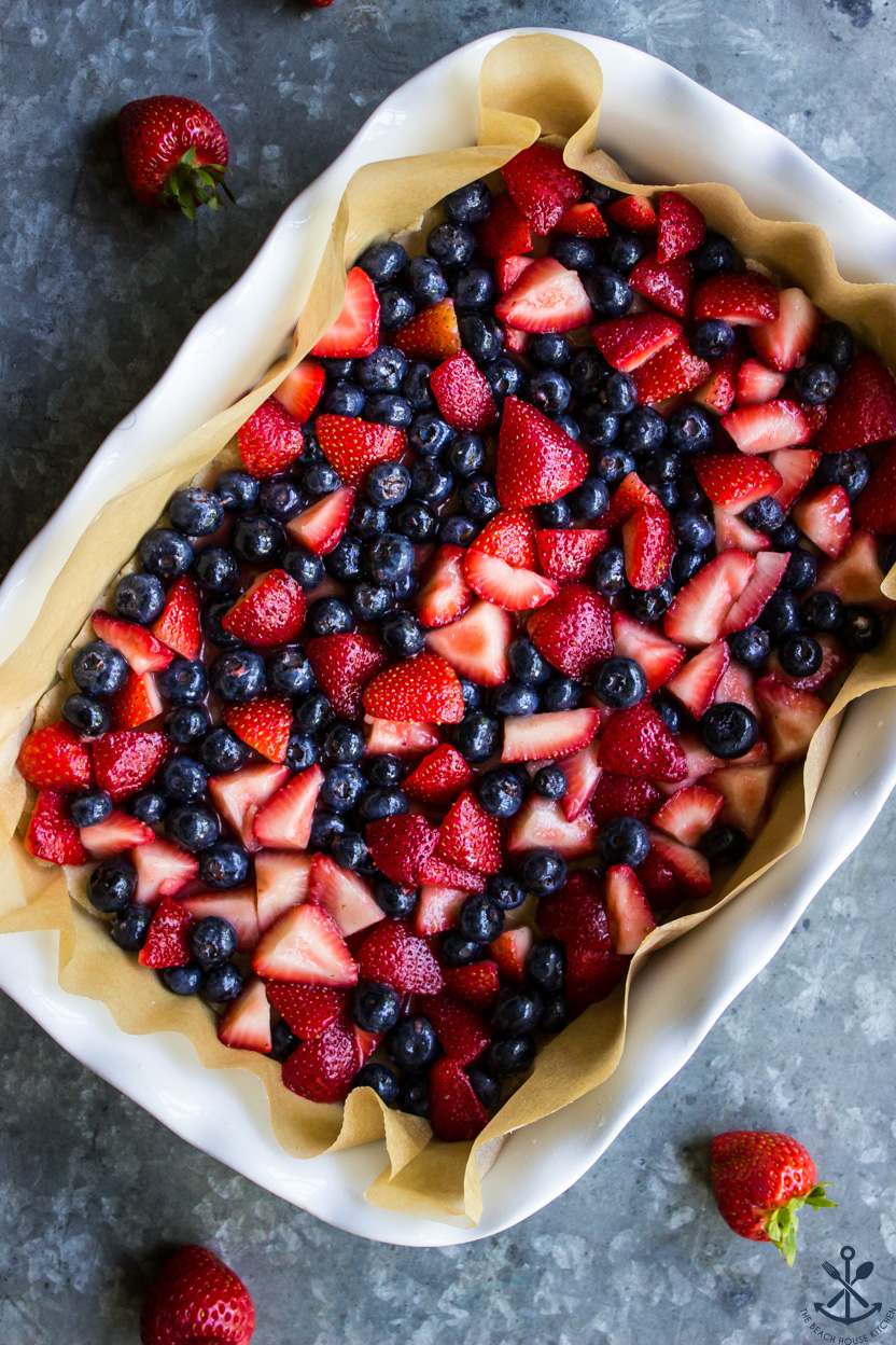 Overhead photo of a baking dish of bars topped with fresh strawberries and blueberries