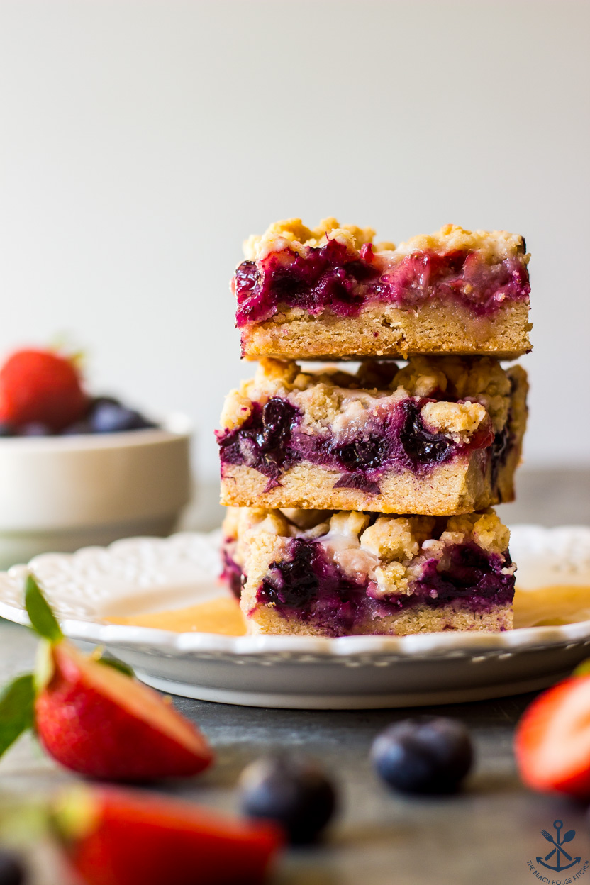 A stack of three berry crumb bars on a plate
