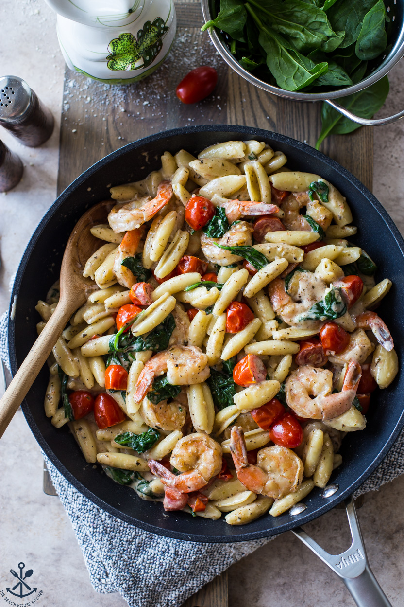Overhead photo of Shrimp Pasta with Garlic Cream Sauce Tomatoes and Spinach in a skillet