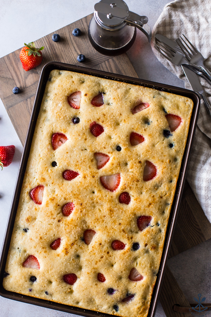 Overhead photo of a sheet pan pancake topped with strawberries and blueberries