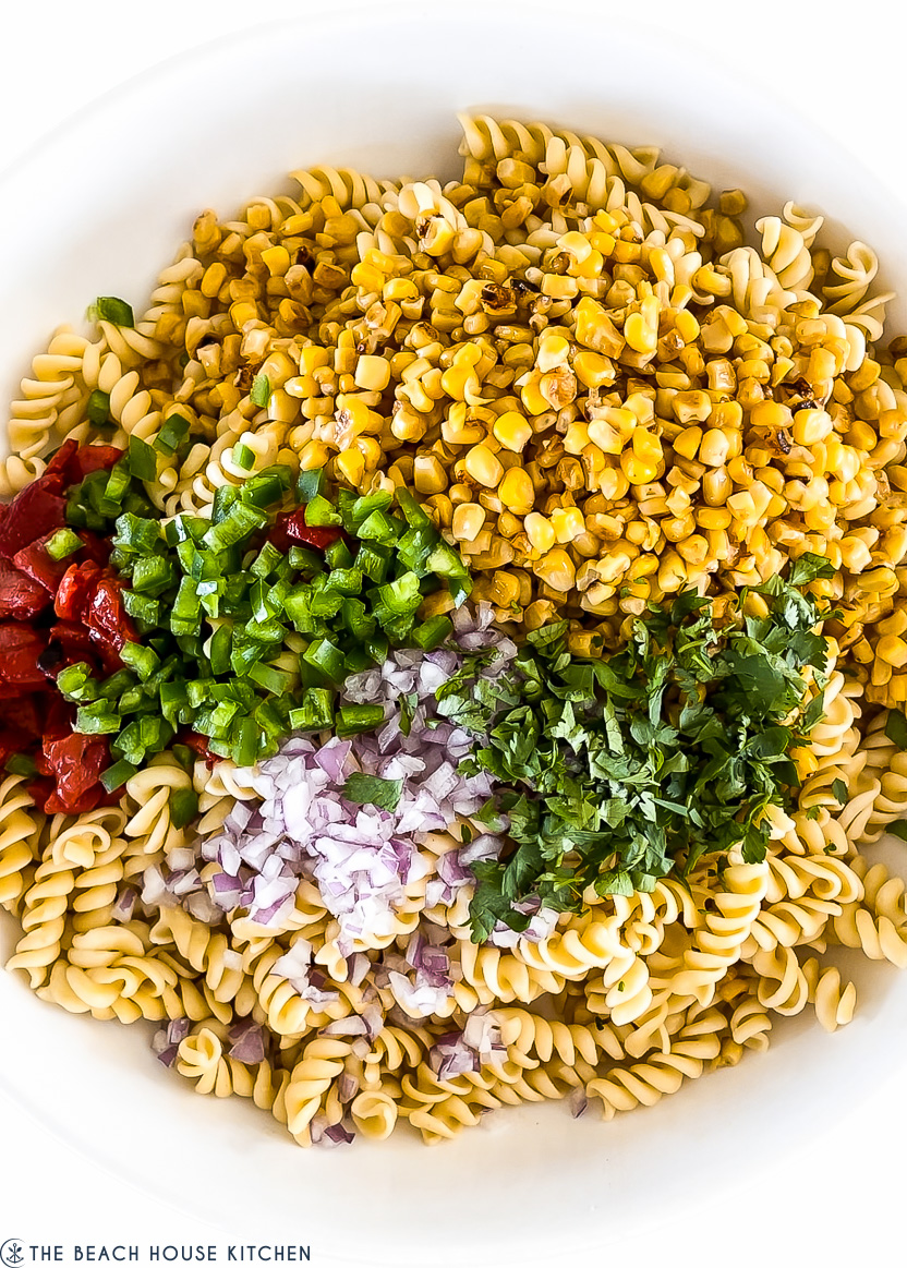 Overhead photo of a bowl of pasta, corn, jalapeno, red pepper, corn and cilantro