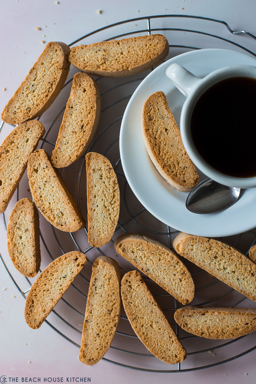 Overhead photo of biscotti slices on a round wire rack with a cup of coffee