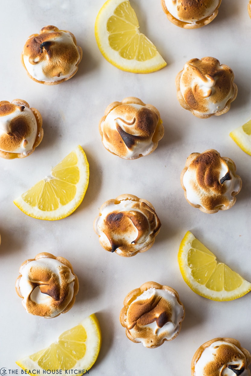 Up close overhead photo of mini lemon meringue pies with lemon slices