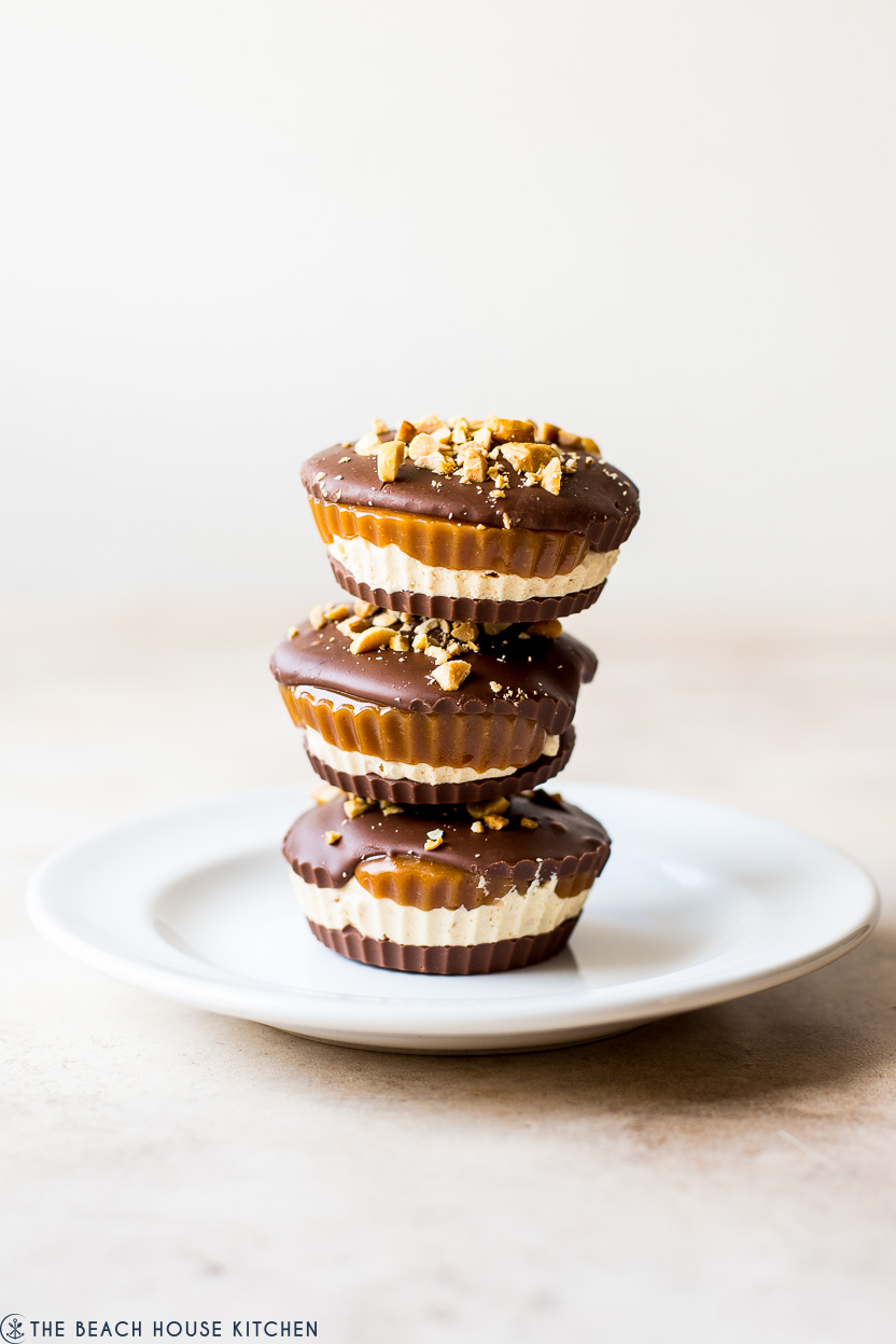 A stack of three homemade snickers cups on a white plate