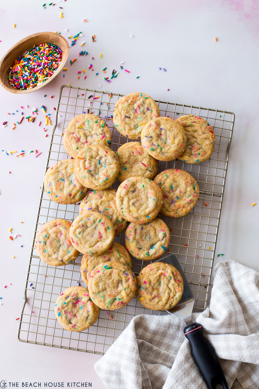 Overhead photos of funfetti cookies on a wire rack with a small wooden bowl of sprinkles off to the left top