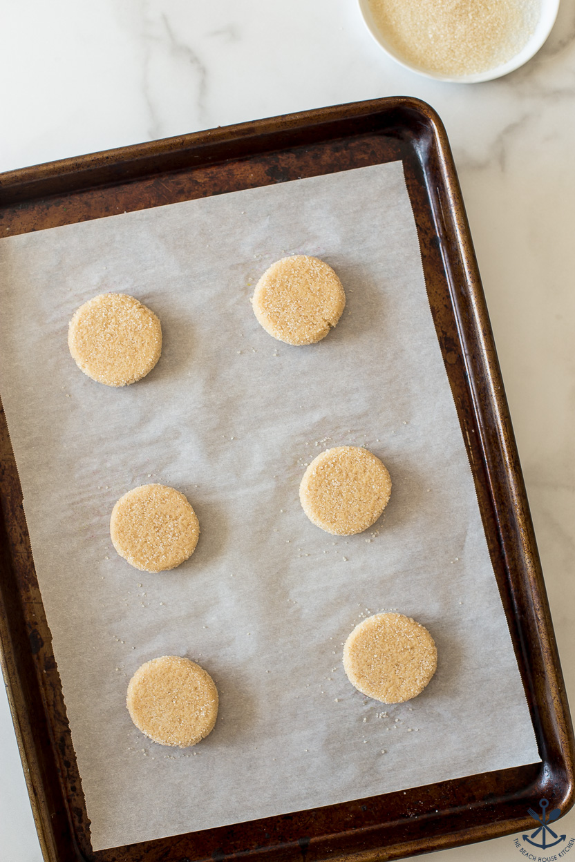 Overhead photo of pre-baked cookies on a baking sheet lined with parchment paper.
